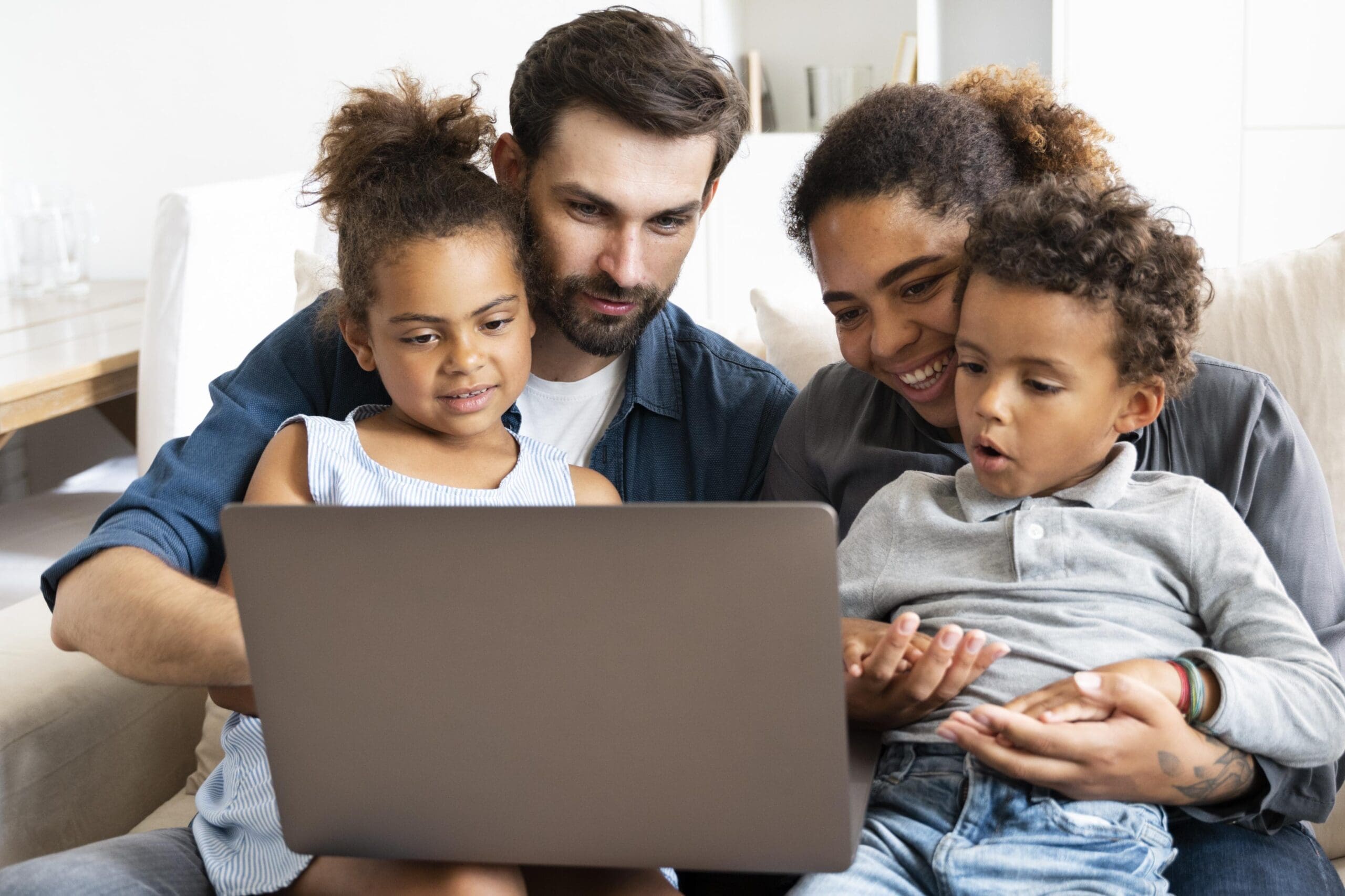 Family of four. Mom, dad and two kids looking at laptop